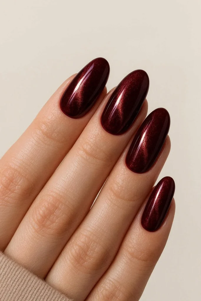 Burgundy velvet cat eye nails with copper shimmer on oval shape