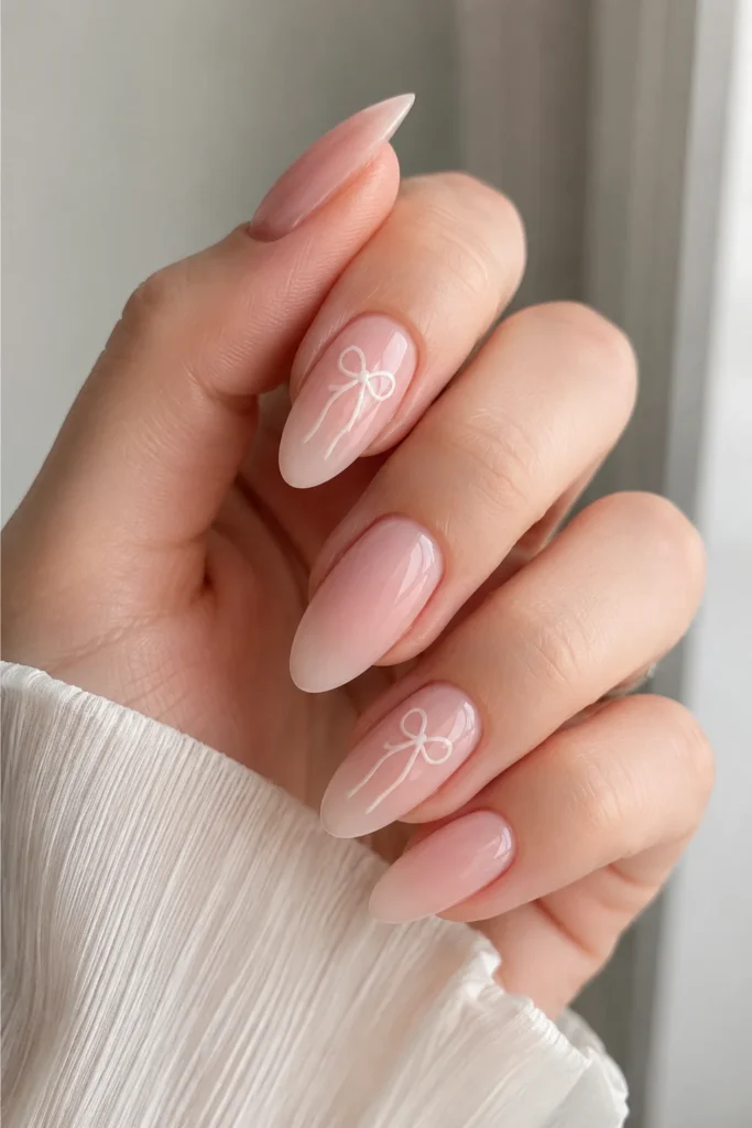 Milky pink nails with subtle ribbon bow accents