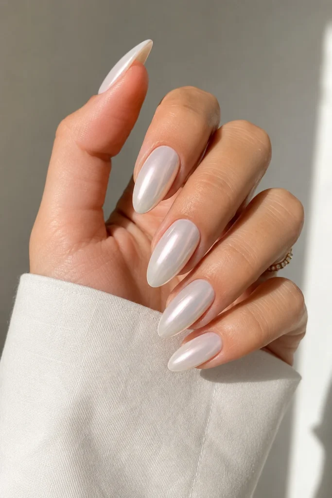 Milky white chrome almond nails with subtle reflective shimmer