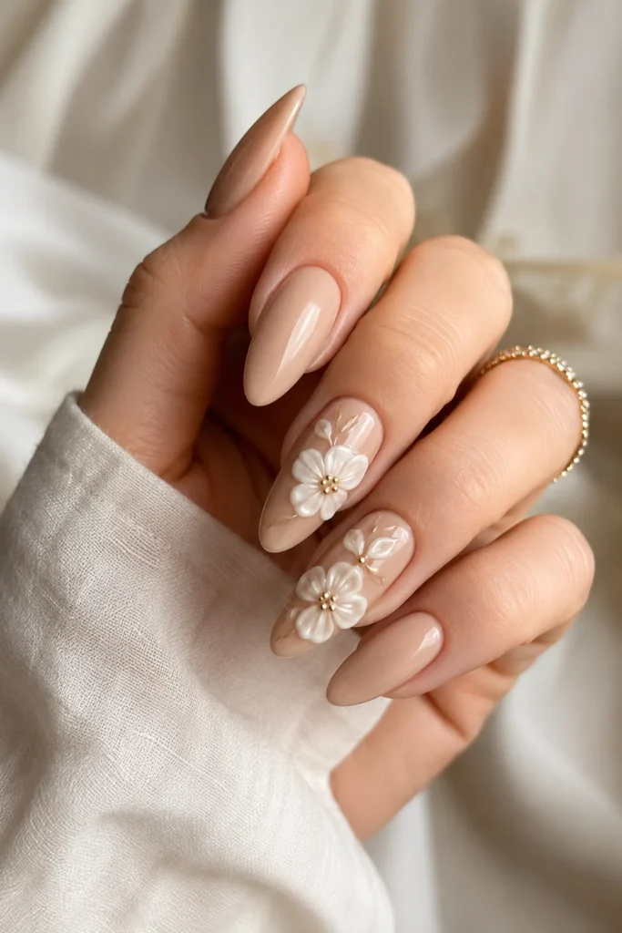 Nude almond nails with sculpted 3D white floral accent details