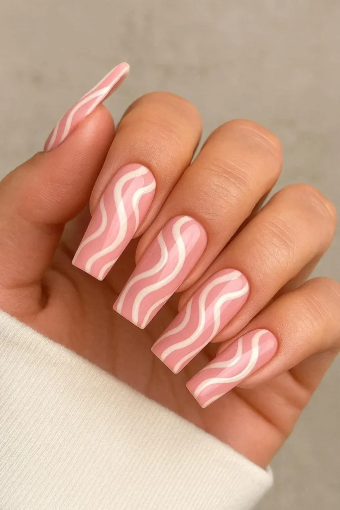 Pink swirl acrylic nail art with hand-painted white fluid design
