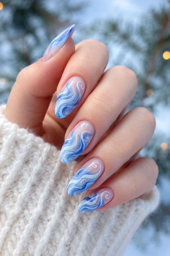 Flowing white and blue swirl nail art with a wintry effect