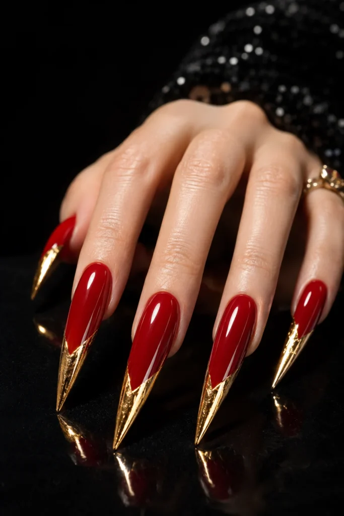 Bold red stiletto nails wrapped with gold foil.