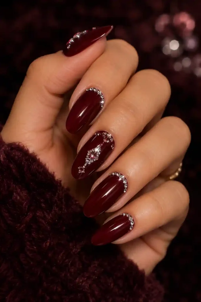 Rich burgundy nails enhanced with sparkling crystal rhinestone accents