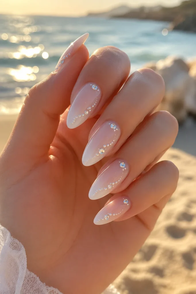 Sparkling crystal embellishments on nude bridal nail design