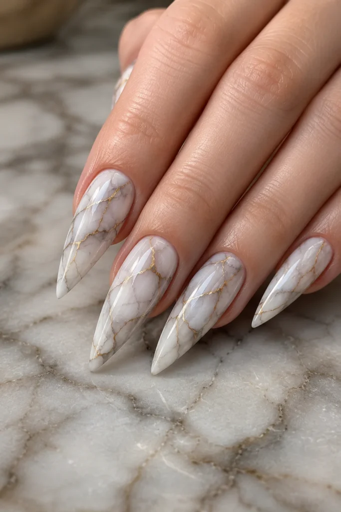 Long pointy marble nails with white gray veining and gold accents