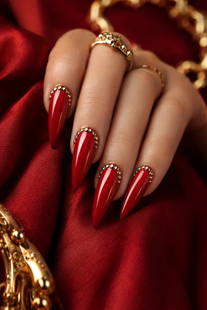 Sharp red stiletto nails with gold stud embellishments