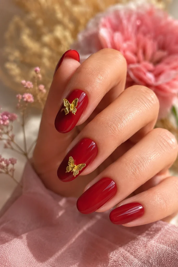 Ruby red nails decorated with gold butterfly charms
