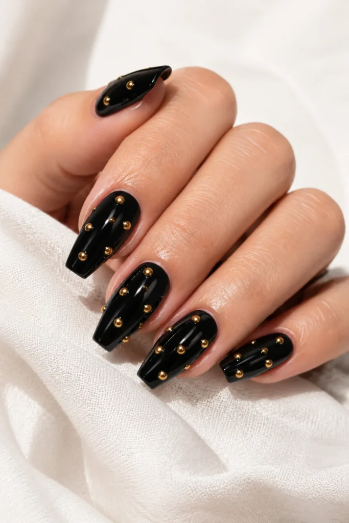 Glossy black nails decorated with small gold studs