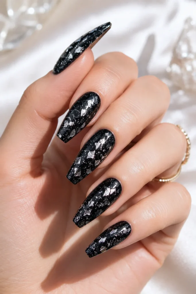 Short black nails decorated with silver foil flecks