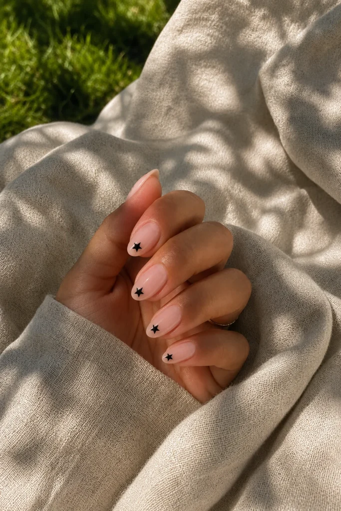 Minimal black star accent nails on sheer nude base