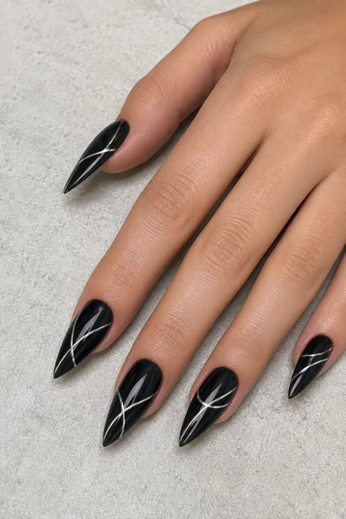 Black stiletto nails featuring delicate silver line art
