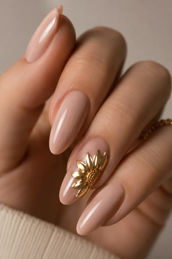 Gold chrome sunflower accent nail on glossy nude almond manicure