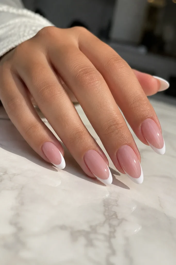 Classic almond white French tip nails with a nude pink base and thin white tips