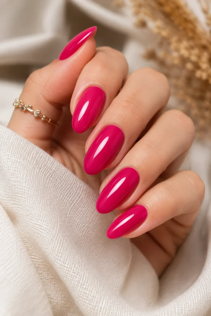 Glossy hot pink almond nails with cream fabric background