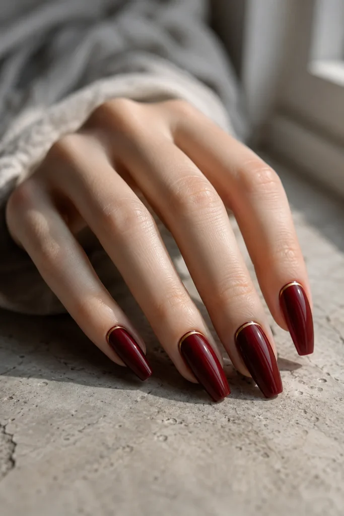 Dark red coffin nails with a thin gold accent line