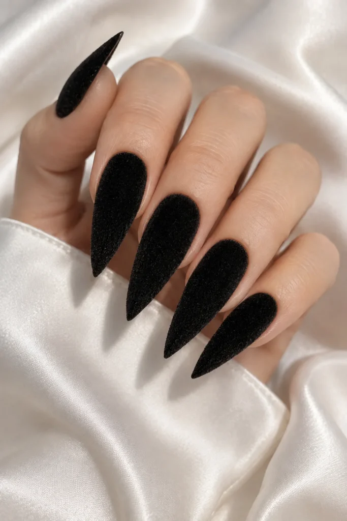 Deep black velvet stiletto nails with textured finish