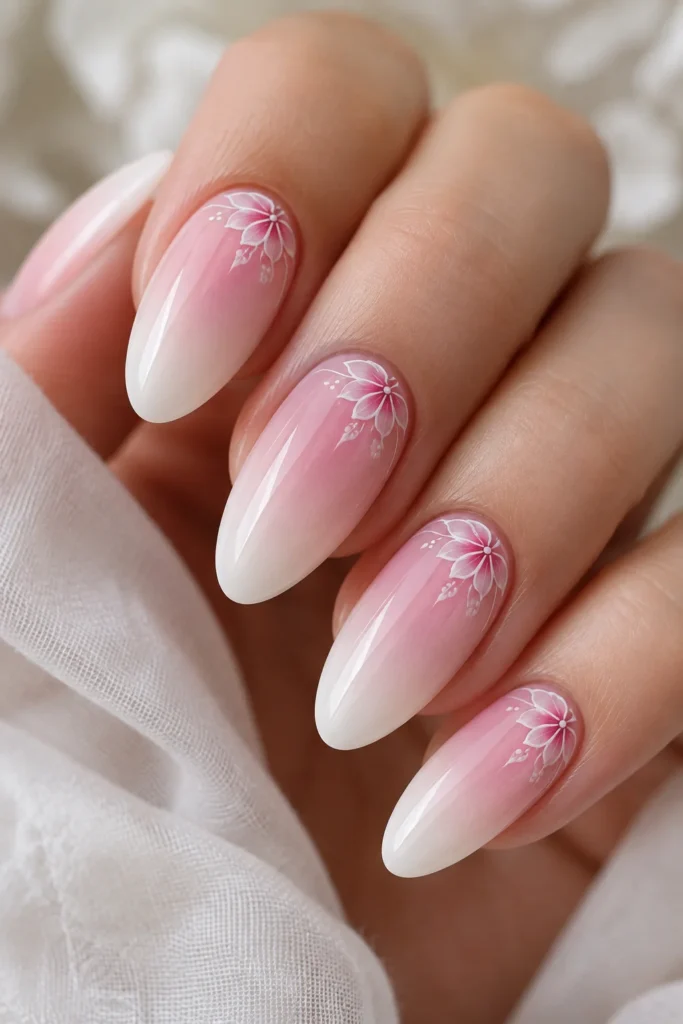 Almond nails with soft pink ombre fade and delicate hand-painted white floral line art