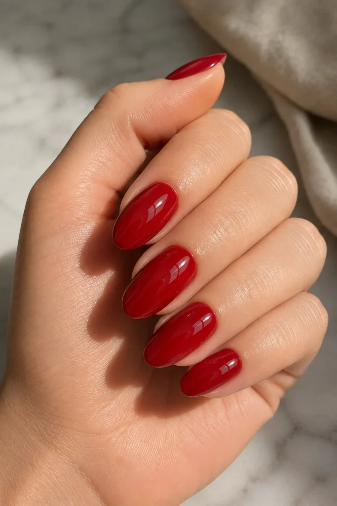 Glossy cherry red nails on medium almond-shaped nails