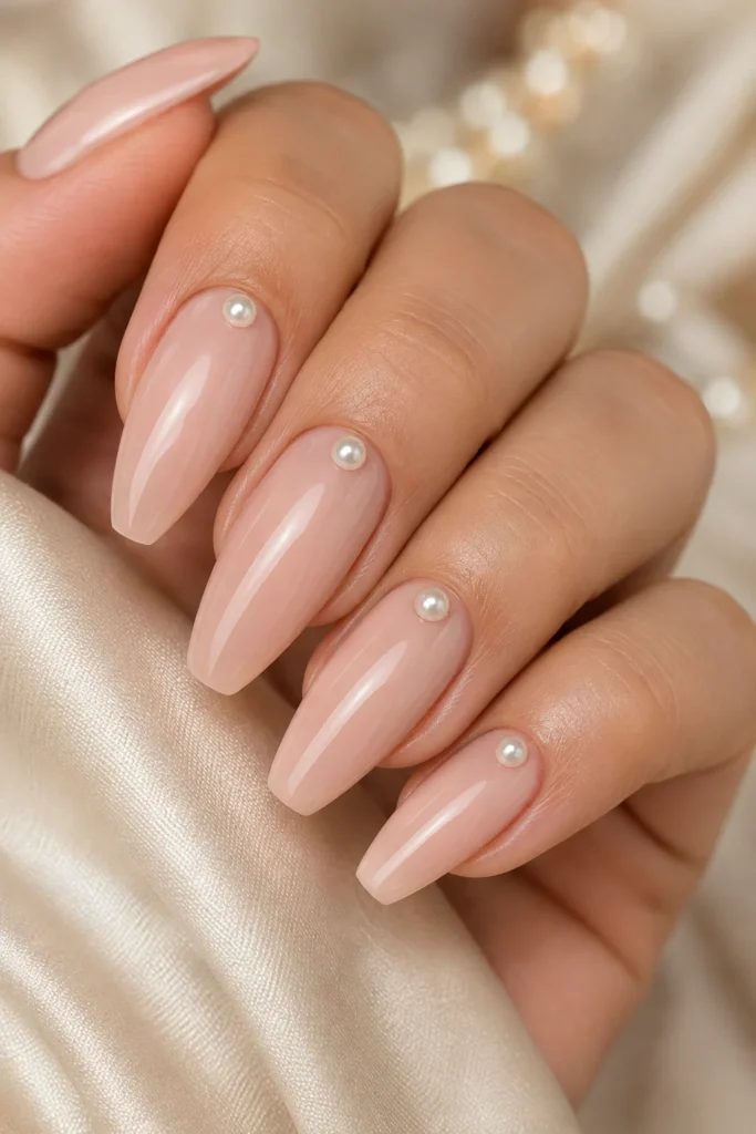 Pearl accent pink nails on almond shaped nails with small pearl detail