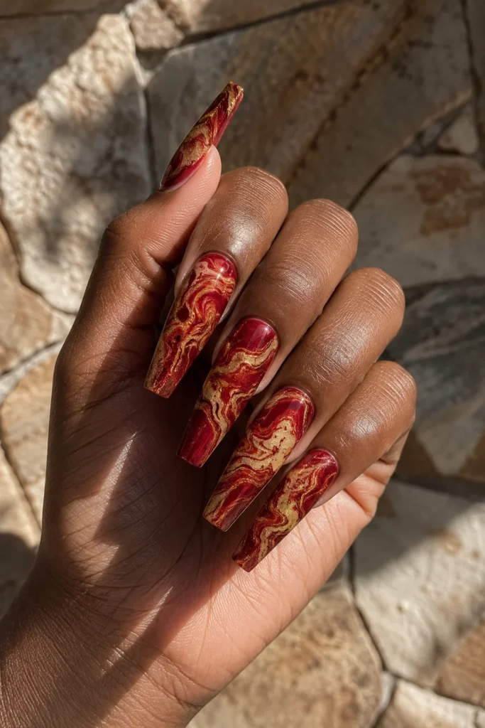Red and gold marble nails on dark skin