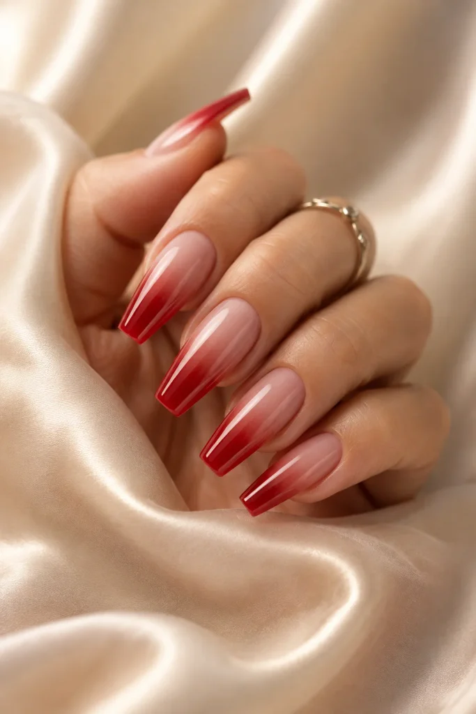 Red ombre nails fading into a nude base
