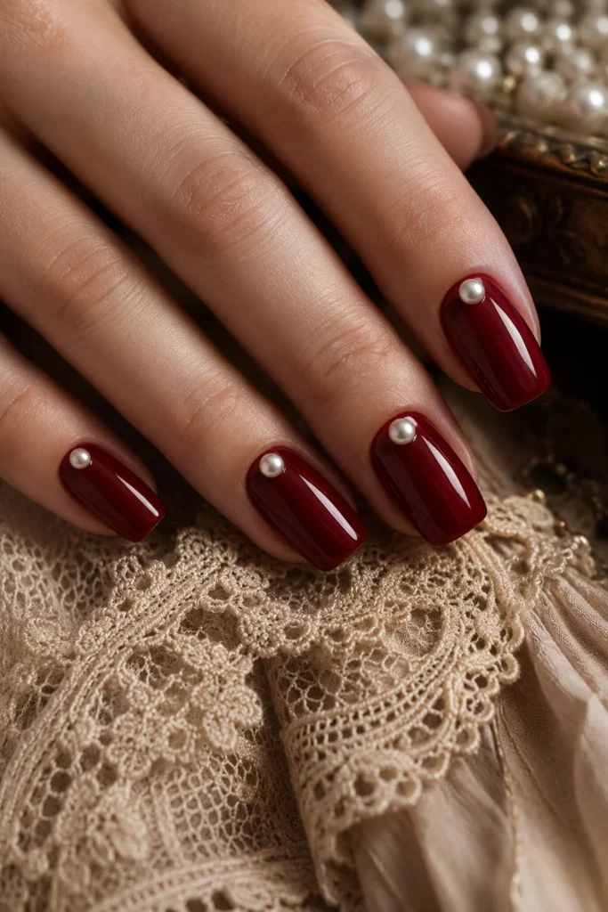 Ruby red wedding nails decorated with delicate pearl accents