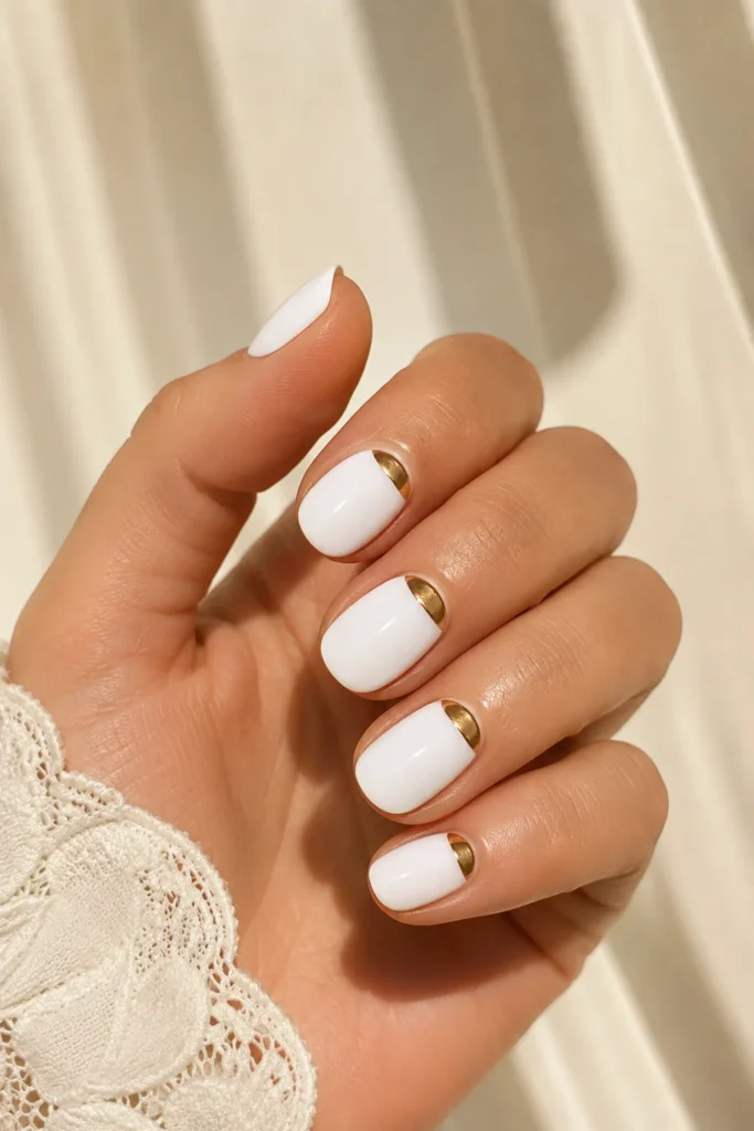 White nails featuring elegant gold half moon accents