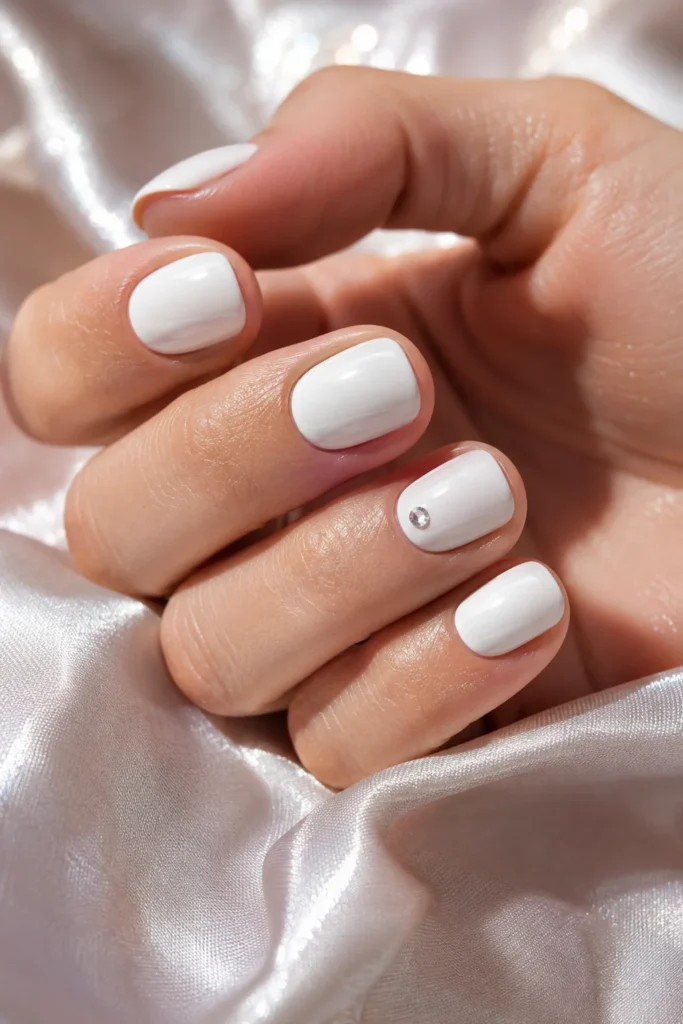 White manicure with a single rhinestone accent