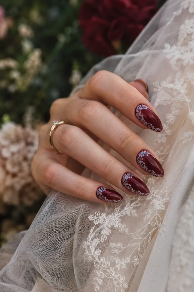 Wine red wedding nails featuring delicate white lace nail art