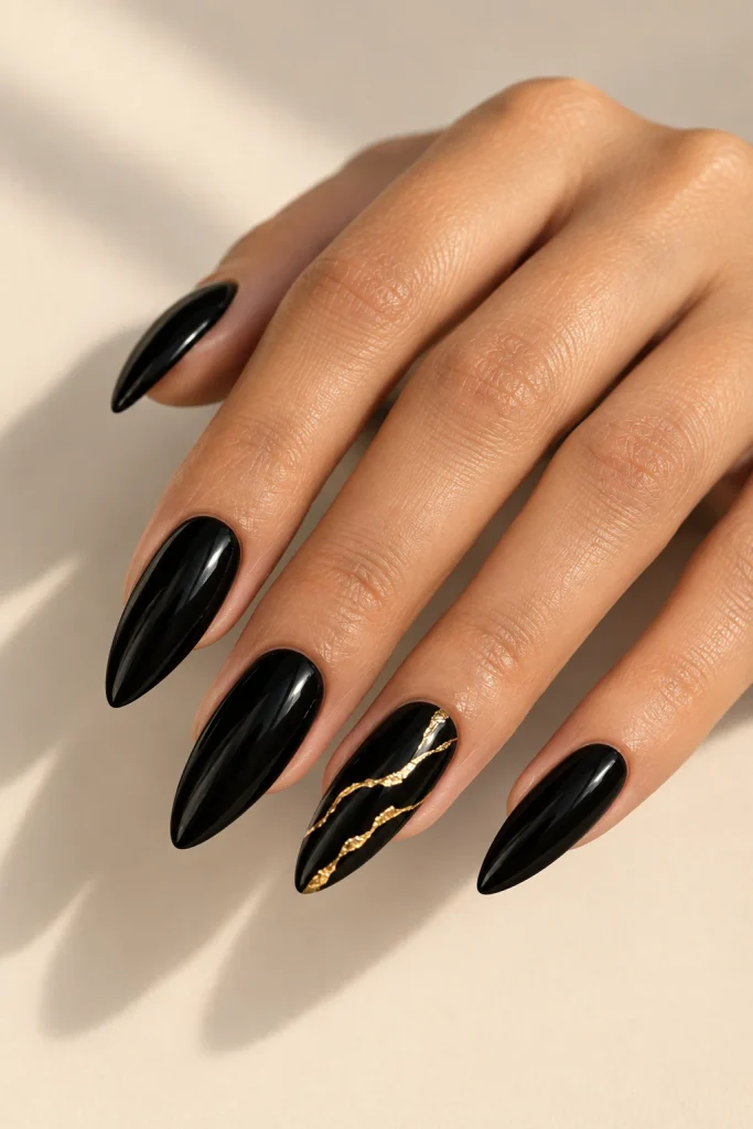 Black almond nails with delicate gold foil accents