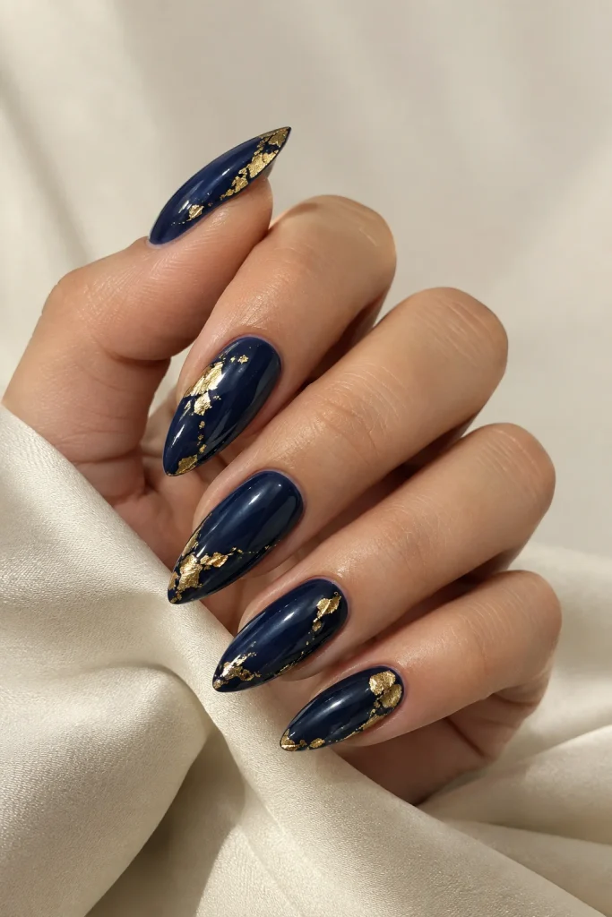 Dark blue nails decorated with delicate gold foil accents