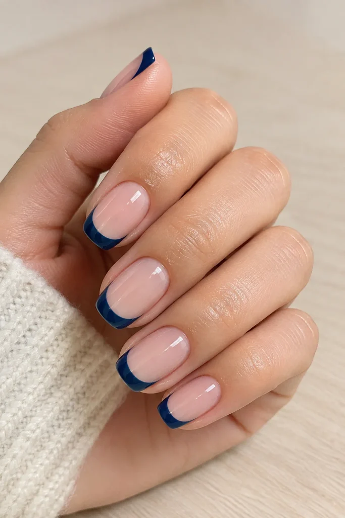 Navy blue French tip nails with a nude base