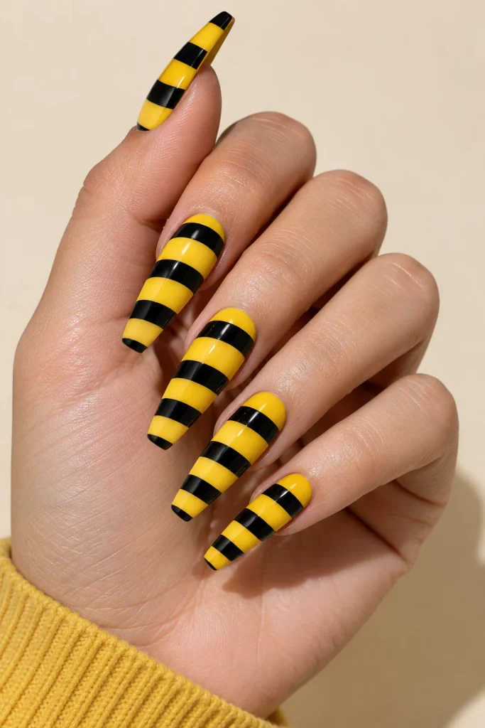 Yellow and black bee-inspired coffin nails with striped accents