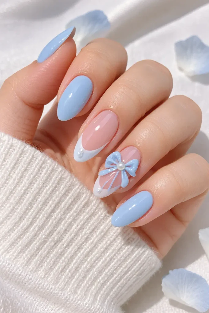 Sheer glossy almond wedding nails with a sculpted baby blue bow accent.