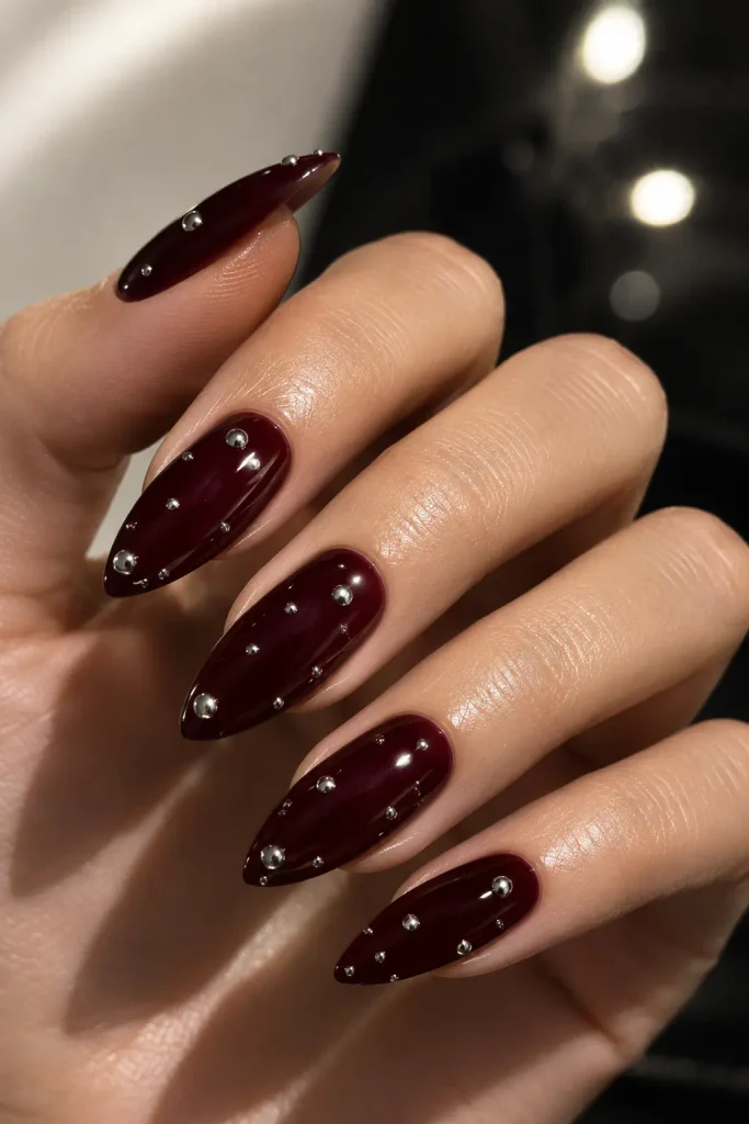 Black cherry nails accented with reflective chrome silver dots