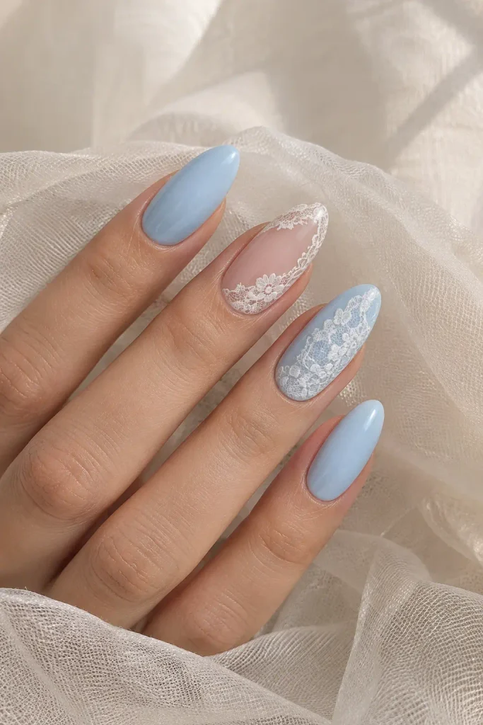 Sheer nude almond nails with delicate white lace over pale blue polish.