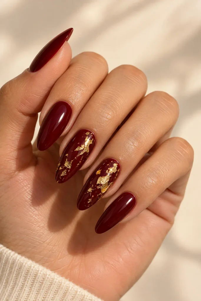 Burgundy nails decorated with delicate gold foil accents