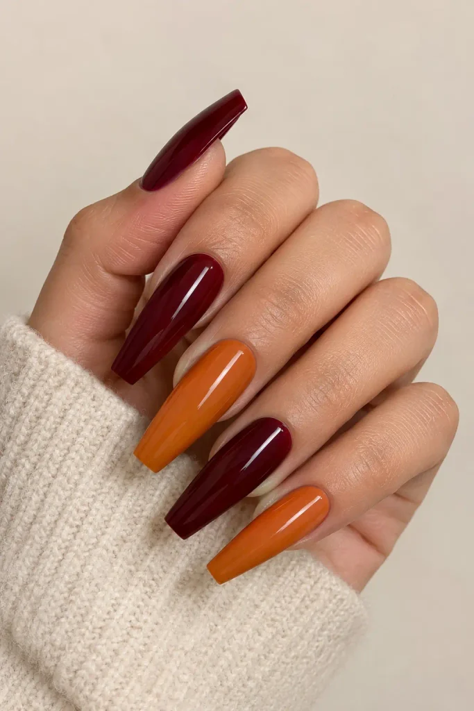 Burgundy and pumpkin orange nails create an elegant contrast