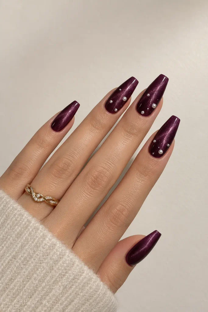 Deep plum velvet nails embellished with small pearl dots