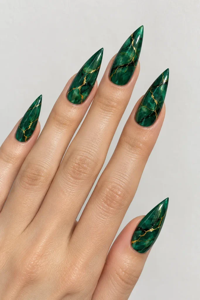 Emerald forest marble stiletto nails with flowing gold veins.