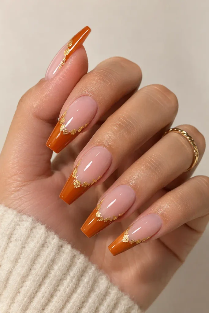 Pumpkin orange French tips feature delicate shimmering gold foil