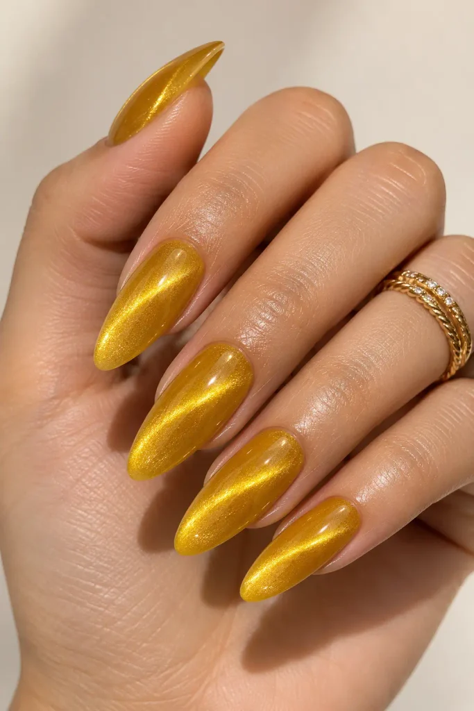 Long almond yellow acrylic nails with magnetic honey gold cat-eye shimmer.
