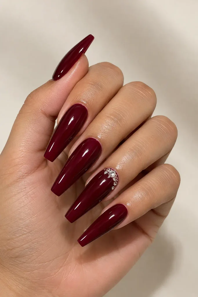 Long coffin burgundy nails adorned with sparkling crystal details