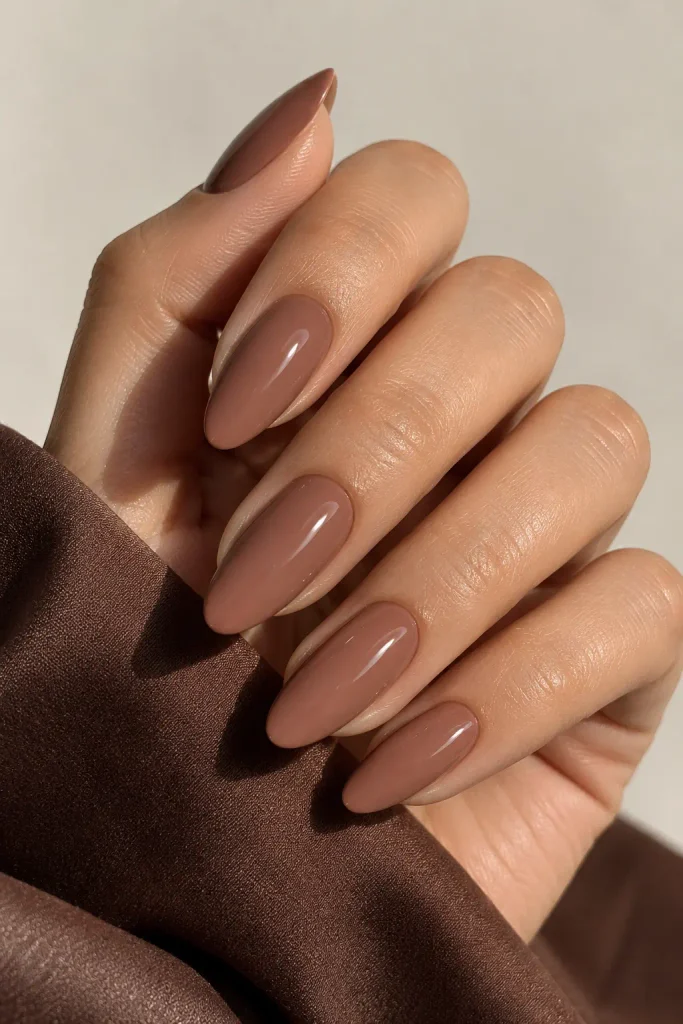 Medium almond nails painted creamy mocha brown with glossy shine