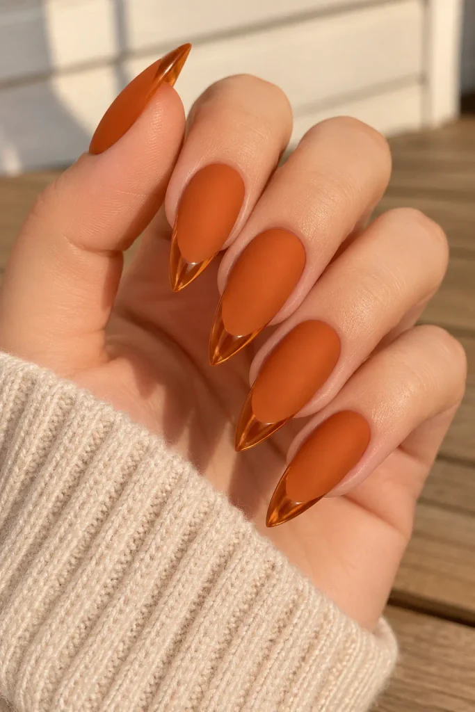 Pumpkin orange matte stiletto nails finished with glossy tips.