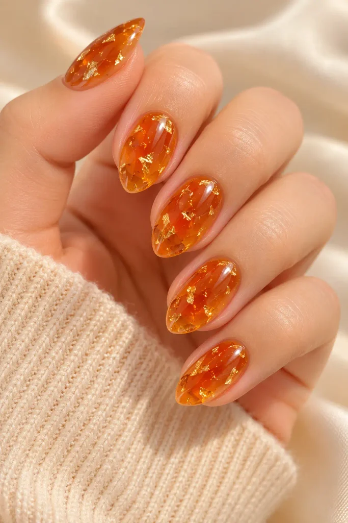 Sheer orange jelly nails sparkle with delicate gold flakes