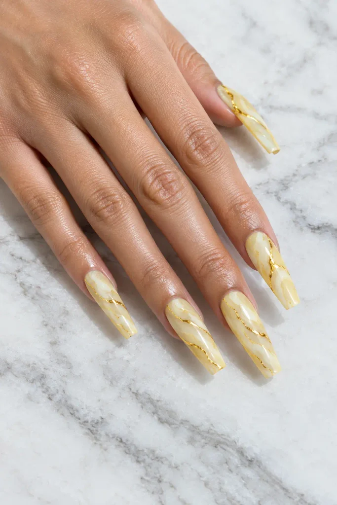 Long coffin yellow acrylic nails with creamy marble swirls and delicate gold veins.